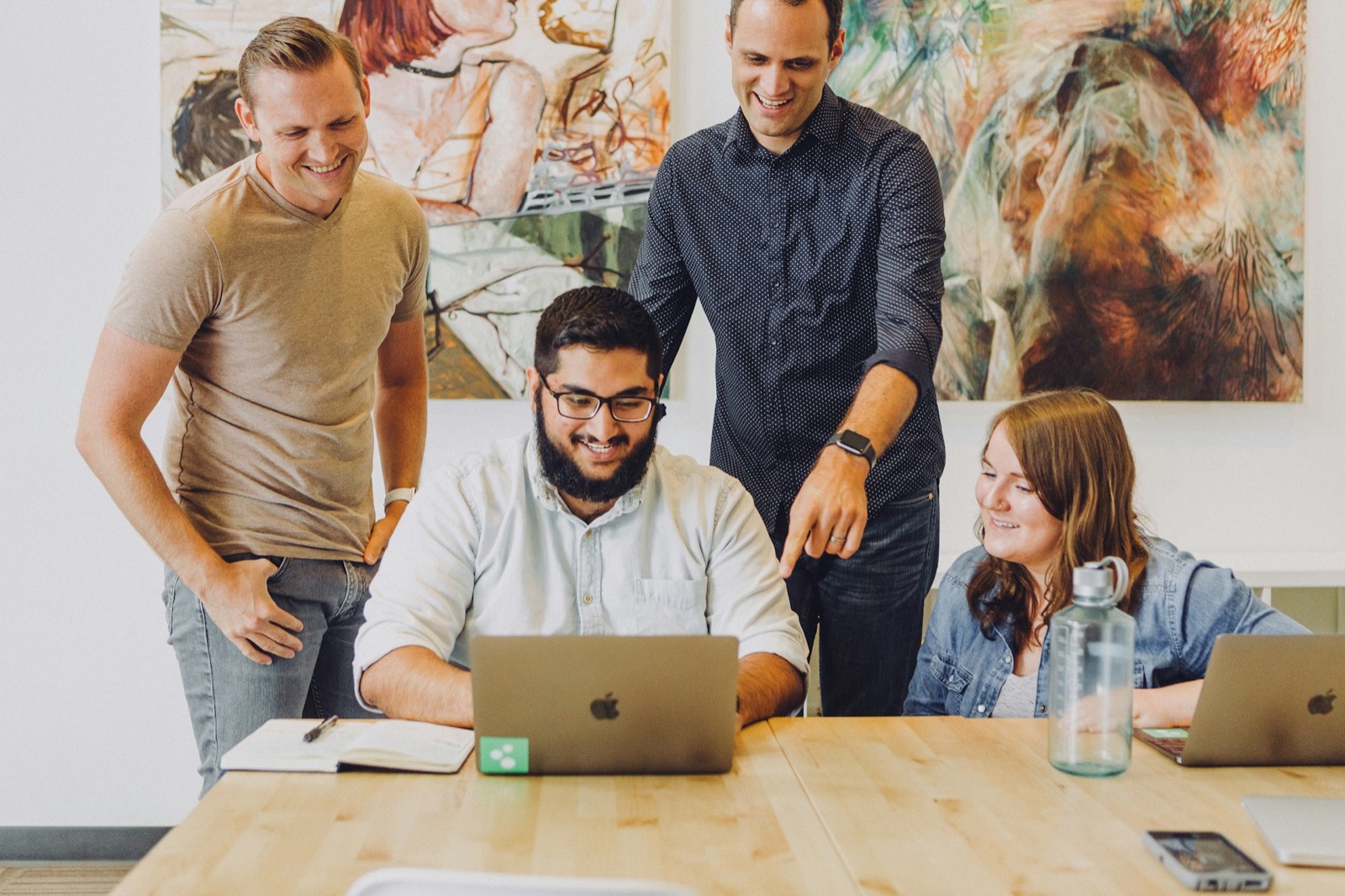 A marketing team gathered around a laptop, reacting to work on screen