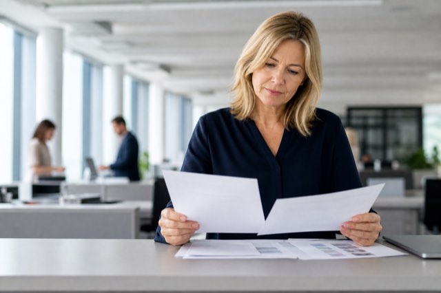 A marketing manager reviewing printed pages in a bright corporate office