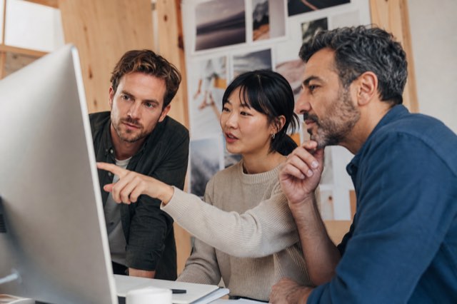 A small agency team reviewing work together on a monitor